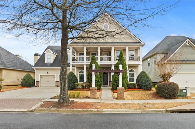 view of front of house with a balcony, an attached garage, ceiling fan, and concrete driveway