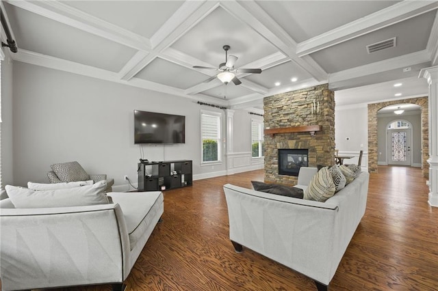 living room featuring a stone fireplace, decorative columns, dark wood-style floors, and coffered ceiling