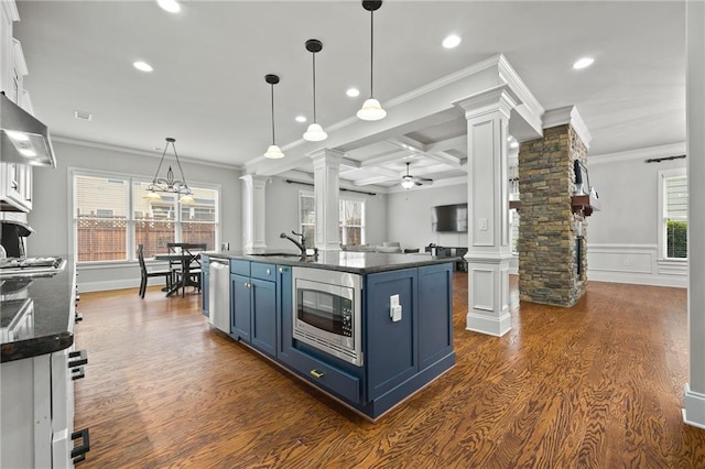 kitchen with blue cabinetry, stainless steel appliances, dark countertops, and ornate columns