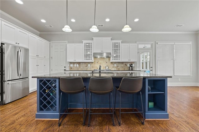 kitchen featuring crown molding, visible vents, stainless steel fridge, and under cabinet range hood