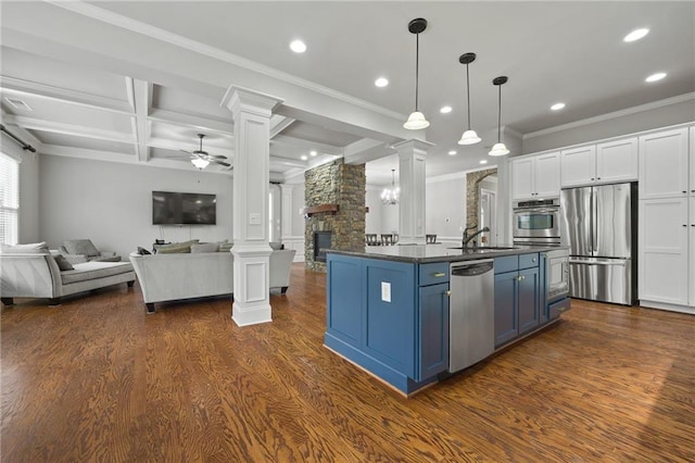 kitchen featuring blue cabinetry, decorative columns, open floor plan, and appliances with stainless steel finishes