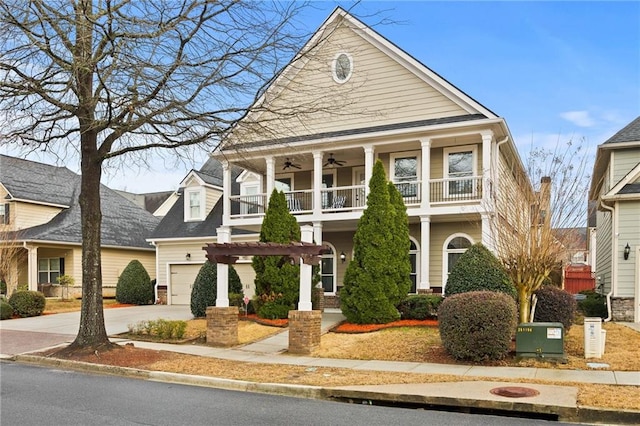 view of front facade with a ceiling fan, a balcony, a garage, and driveway