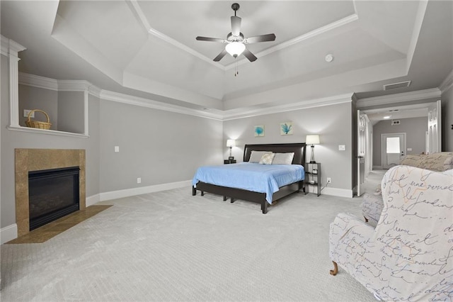 bedroom with visible vents, a fireplace with flush hearth, a tray ceiling, and carpet floors