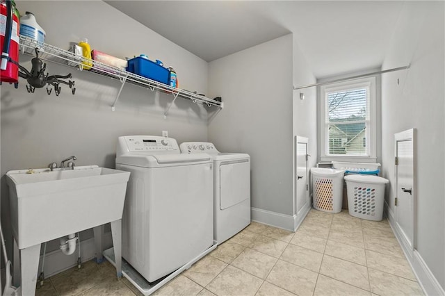 laundry area with washing machine and clothes dryer, tile patterned flooring, baseboards, laundry area, and a sink