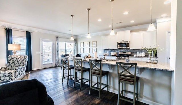 kitchen with white cabinetry, stainless steel appliances, decorative light fixtures, and light stone countertops