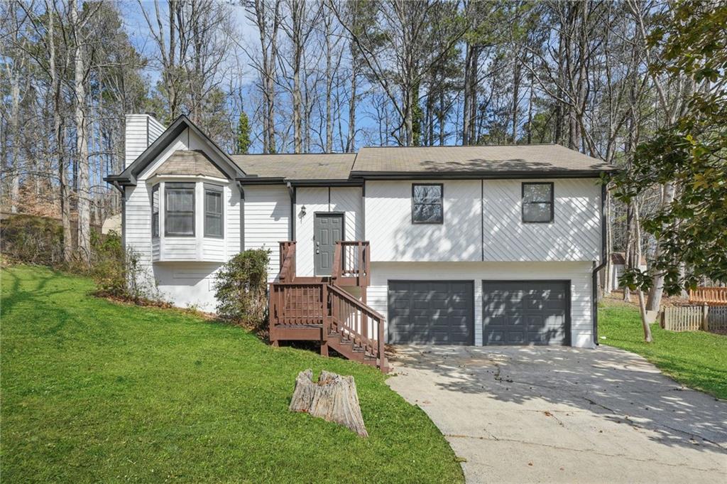 5570 Deerfield Pl NW, Kennesaw, GA 30144 - split foyer home with a front lawn, concrete driveway, a chimney, and a garage