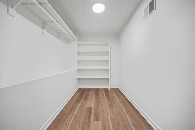 walk in closet with visible vents and wood finished floors