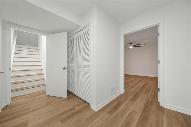 corridor featuring baseboards, stairway, visible vents, and wood finished floors