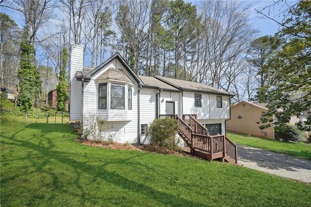 view of front of house featuring a garage, a front lawn, a chimney, and driveway