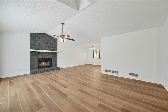 unfurnished living room with wood finished floors, a textured ceiling, visible vents, a fireplace, and a ceiling fan