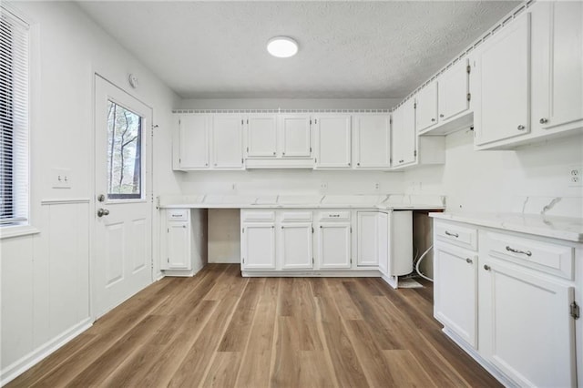 kitchen with white cabinetry, a textured ceiling, and wood finished floors