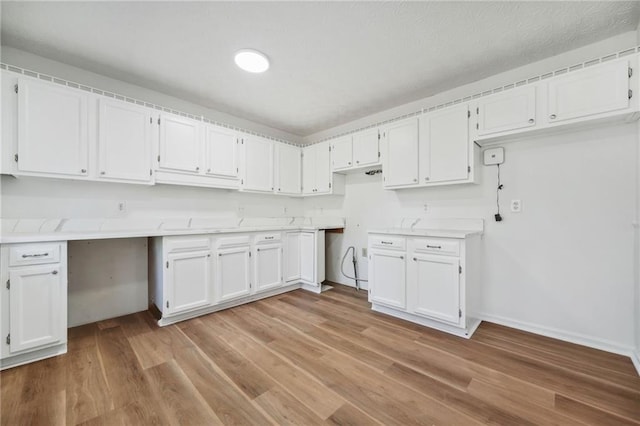 kitchen featuring light wood finished floors, white cabinetry, and baseboards