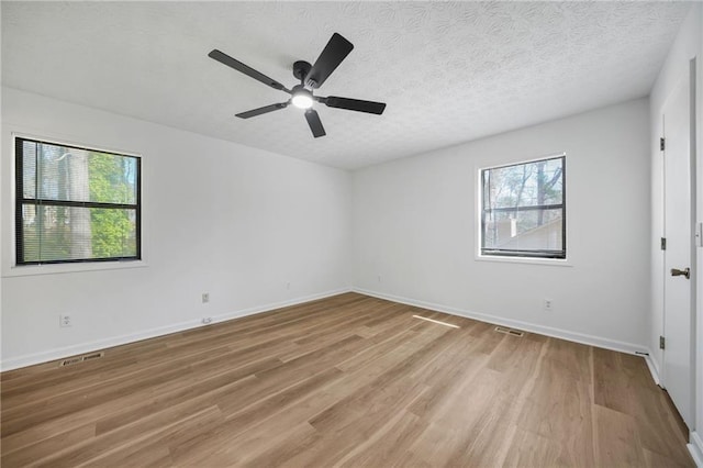 spare room with baseboards, a ceiling fan, visible vents, and light wood-style floors