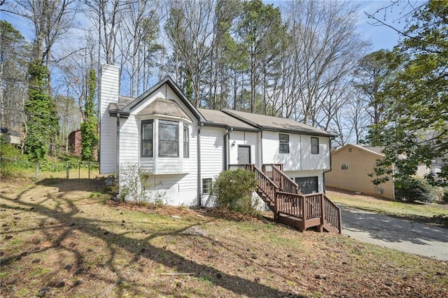 view of front of home featuring driveway, a chimney, a garage, and stairs