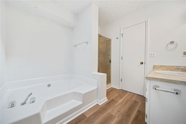 full bath with wood finished floors, a stall shower, a bath, a textured ceiling, and vanity