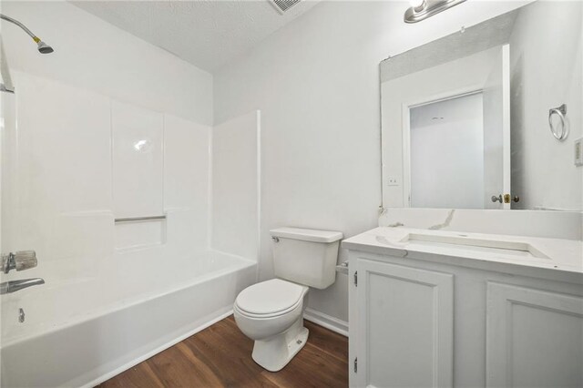 bathroom featuring toilet, visible vents, vanity, tub / shower combination, and wood finished floors