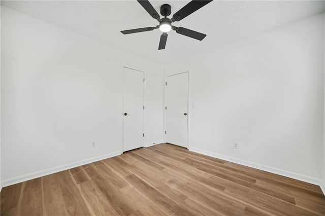 empty room featuring baseboards, light wood finished floors, and ceiling fan