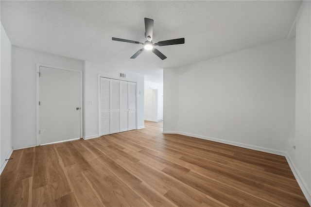 unfurnished bedroom featuring a closet, light wood-type flooring, visible vents, baseboards, and ceiling fan
