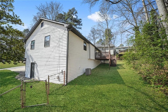 view of side of home featuring a gate, fence, a lawn, a wooden deck, and stairway