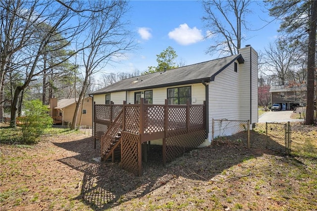 rear view of property featuring a gate, fence, a chimney, a deck, and stairs