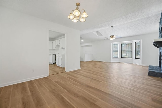 unfurnished living room featuring light wood-style flooring, a textured ceiling, ceiling fan with notable chandelier, and baseboards