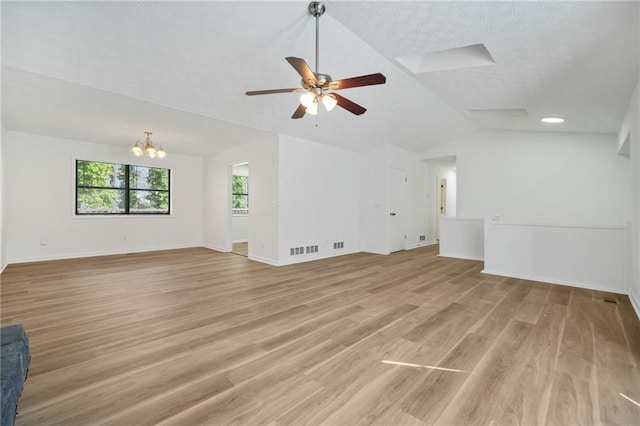 empty room featuring light wood finished floors, ceiling fan with notable chandelier, a textured ceiling, visible vents, and lofted ceiling