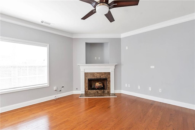 unfurnished living room featuring hardwood / wood-style flooring, a premium fireplace, and crown molding