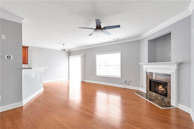 unfurnished living room with ceiling fan, light hardwood / wood-style floors, ornamental molding, and a high end fireplace