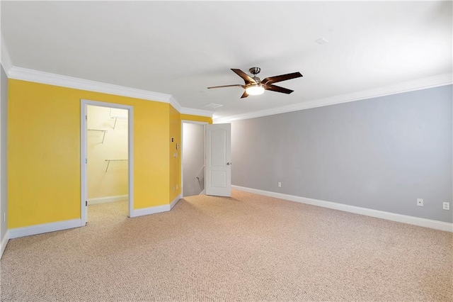 unfurnished bedroom featuring carpet, a walk in closet, ceiling fan, crown molding, and a closet