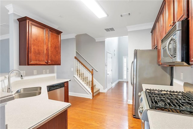 kitchen featuring light wood-type flooring, ornamental molding, sink, and appliances with stainless steel finishes