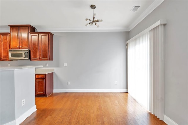 kitchen with light hardwood / wood-style flooring, hanging light fixtures, a notable chandelier, and ornamental molding