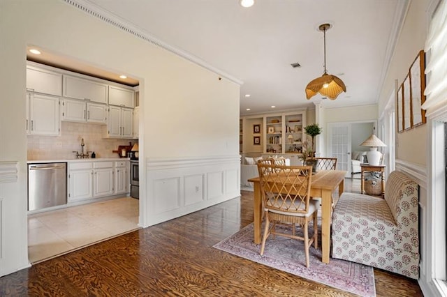 dining room featuring wood-type flooring, crown molding, and sink