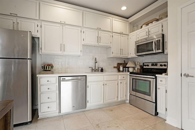 kitchen featuring backsplash, sink, light tile patterned floors, white cabinetry, and stainless steel appliances