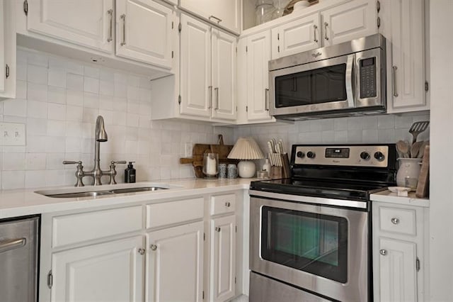 kitchen with backsplash, white cabinetry, sink, and appliances with stainless steel finishes