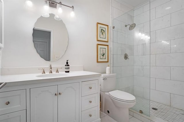 bathroom featuring tile patterned flooring, vanity, toilet, and tiled shower