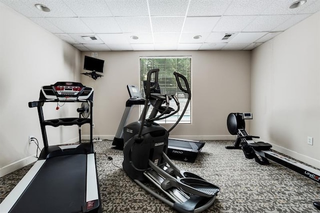 exercise area featuring carpet flooring and a drop ceiling