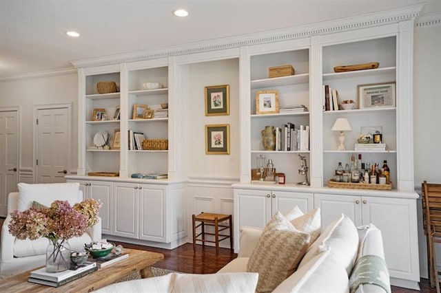 living area featuring bar area, built in shelves, dark wood-type flooring, and ornamental molding