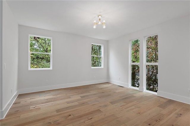 spare room with light hardwood / wood-style floors and a notable chandelier