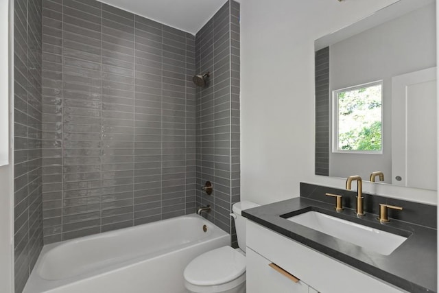 full bathroom with vanity, tiled shower / bath combo, and toilet