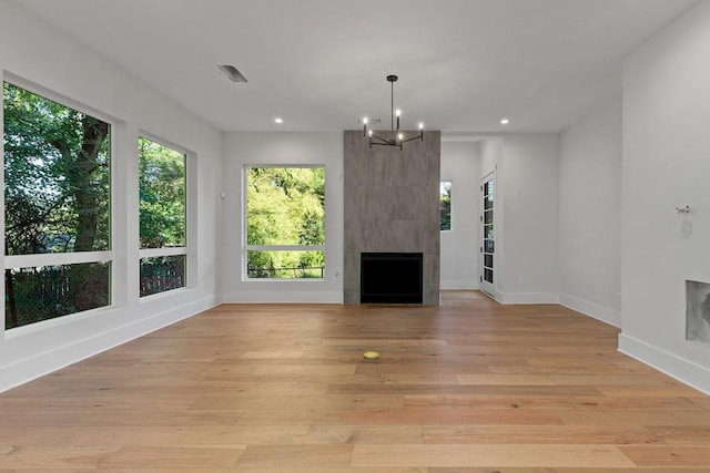 unfurnished living room with light wood-type flooring, a chandelier, and a fireplace