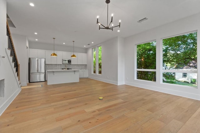 kitchen with appliances with stainless steel finishes, sink, an inviting chandelier, and light wood-type flooring