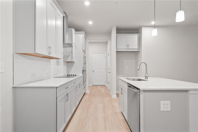 kitchen with sink, appliances with stainless steel finishes, pendant lighting, a kitchen island with sink, and white cabinets