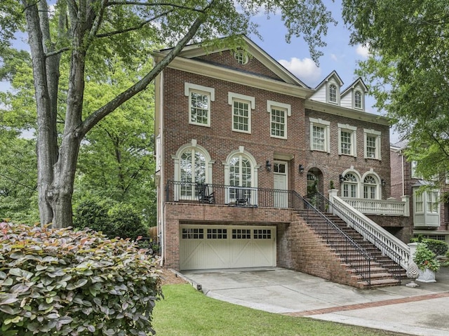 colonial-style house with a garage, brick siding, driveway, and stairway