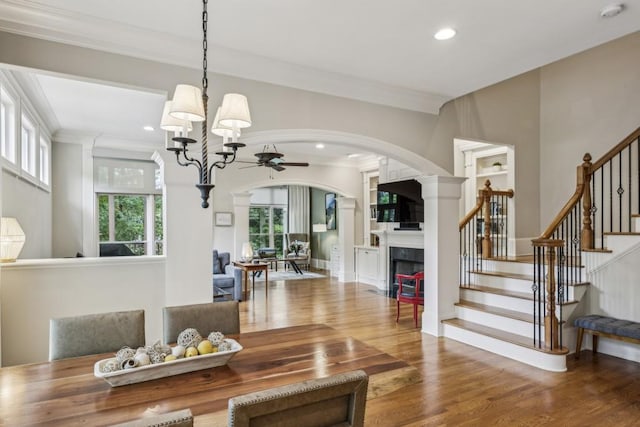 dining room featuring a ceiling fan, arched walkways, wood finished floors, crown molding, and stairway
