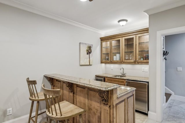 indoor wet bar featuring stainless steel dishwasher, ornamental molding, baseboards, and beverage cooler