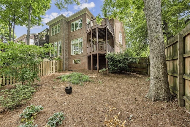rear view of property featuring a fenced backyard, brick siding, and a balcony