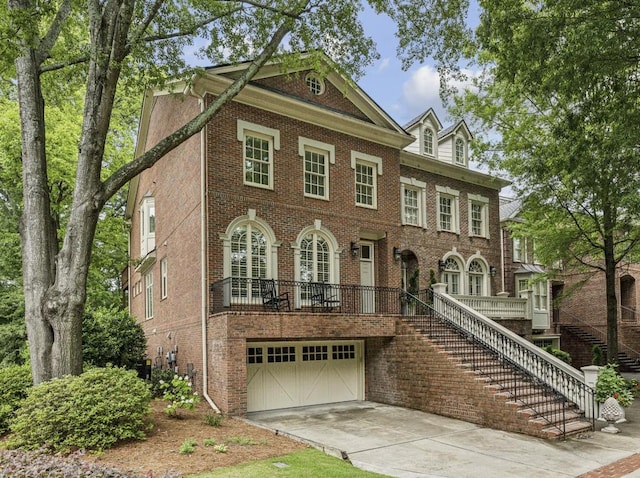 colonial-style house featuring an attached garage, brick siding, driveway, and stairs