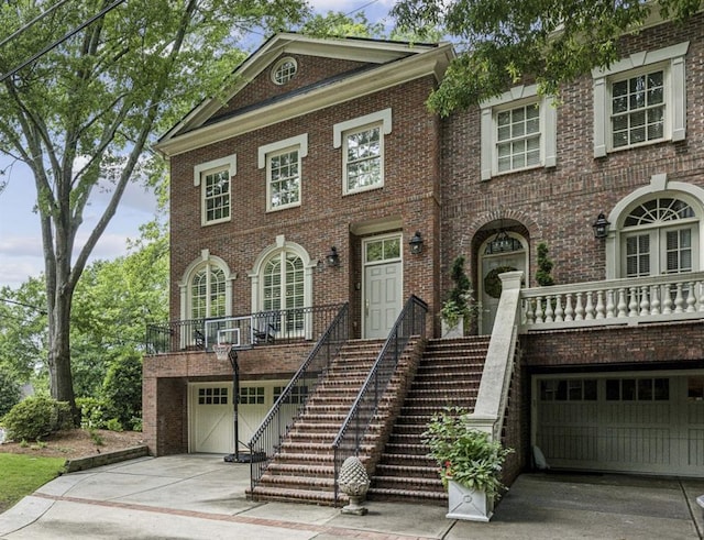 georgian-style home with an attached garage, driveway, stairs, and brick siding