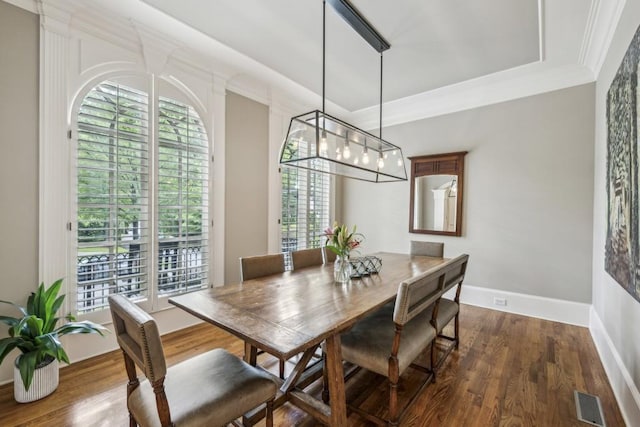 dining space with dark wood-type flooring, crown molding, and baseboards