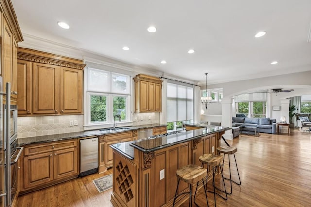 kitchen with a kitchen breakfast bar, a center island, open floor plan, a sink, and backsplash